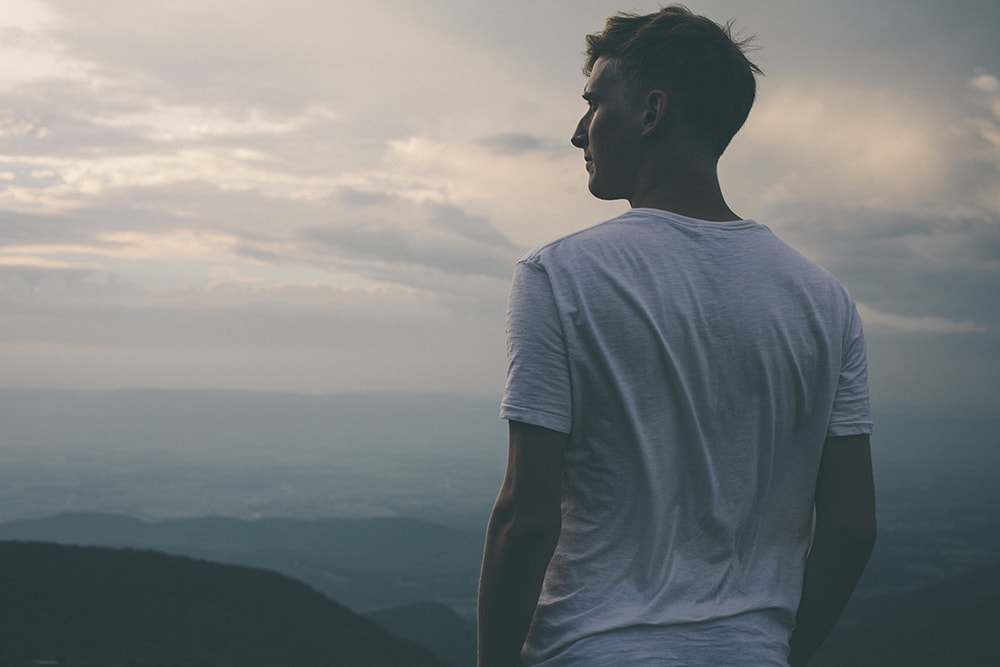 man looking at sunset on mountain